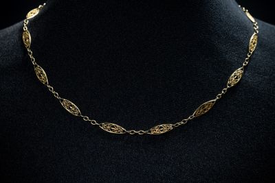 a gold chain necklace with leaves on a mannequin mannequin