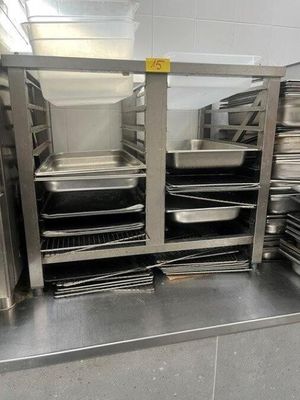 several trays of food are stacked on a metal shelf in a kitchen