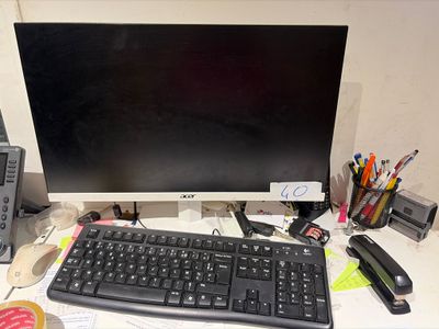 a computer monitor and keyboard on a desk with other office supplies