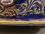 a blue and gold vase with a shell on it