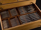 a wooden box filled with silverware on a black surface