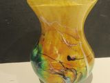 un vase jaune posé sur une table blanche, sur fond noir