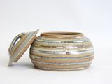 a small pot with a lid sitting on a white surface