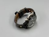 the watch is black and has a brown leather band