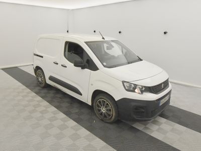 La camionnette blanche est garée dans le garage, sur le sol à damier.