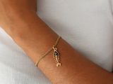 a close up of a person wearing a gold bracelet with a fish on it