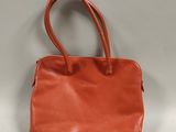 an orange leather handbag on a white background