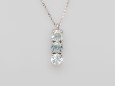 a three stone pendant with a chain on a white background