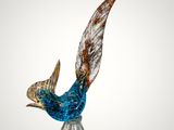 glass sculpture of a bird on a clear base on a white background