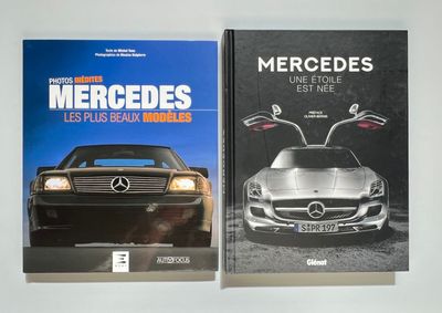 deux livres posés sur une surface blanche, avec une voiture et une Mercedes