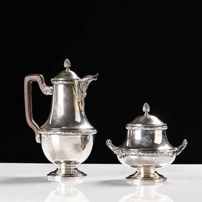 deux théières en argent et une soucoupe posées sur une table blanche
