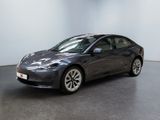 La Tesla Model 3 est garée dans une pièce au sol noir.