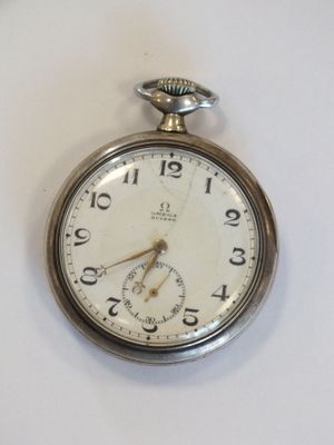 une montre de poche en argent posée sur une surface blanche