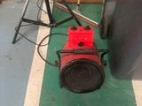 un ventilateur rouge posé par terre à côté d'un trépied