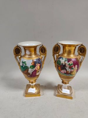une paire de vases en or ornés de scènes peintes, posés sur une table