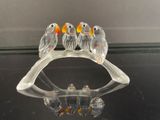 une figurine en verre représentant un groupe d'oiseaux perchés sur une branche