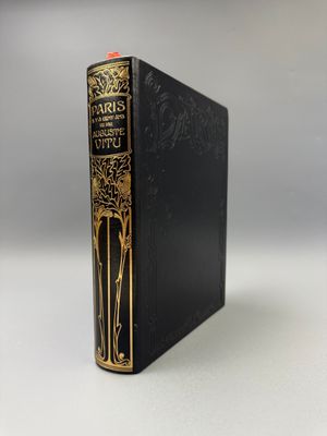 un livre noir aux bords dorés posé sur une table blanche