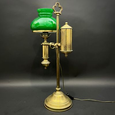 une lampe de table ancienne en laiton avec un abat-jour en verre vert sur fond noir
