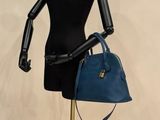 a mannequin holding a blue purse on a stand