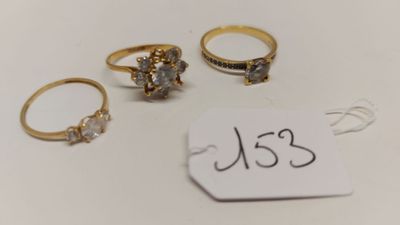 trois bagues en or serties de diamants, accompagnées d'une étiquette de prix, posées sur un fond blanc