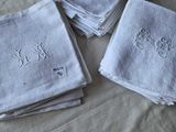 quatre serviettes blanches ornées de monogrammes brodés, posées sur un lit