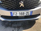 the front end of a silver car with a number plate on it