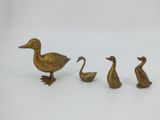 three brass ducks are standing next to each other on a white surface