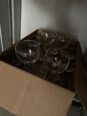 de nombreux verres à vin vides dans une boîte posée par terre