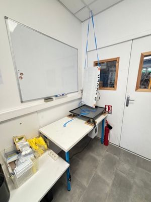 un tableau blanc accroché au mur dans une pièce équipée d'une table et de chaises