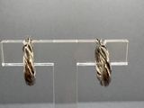 pair of silver and gold hoop earrings on a clear acrylic stand