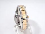 a silver and gold watch on a clear stand