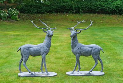 deux statues de cerfs posées sur un socle dans l'herbe