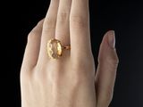 woman ' s hand wearing a gold ring with a yellow stone