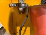 a red tank with a hose attached to it next to a yellow container
