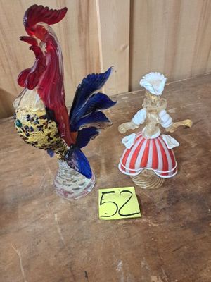 deux figurines représentant un coq et une femme, posées sur une table