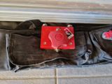 un objet rouge dans un sac noir posé par terre