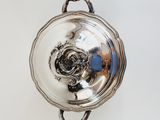 a silver plate with a rose in it on a white surface