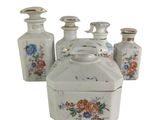 four white vases with flowers on them sitting next to each other