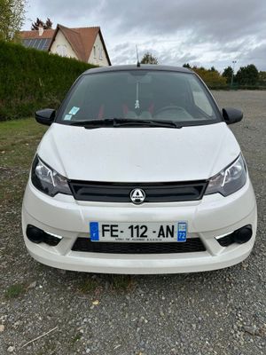 the front of a white car parked on a gravel road