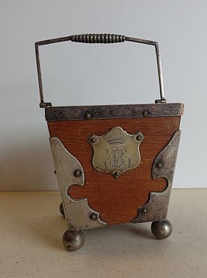 une petite boîte en bois munie d'une poignée en métal, posée sur une table