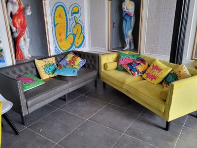deux canapés et une table dans une pièce où sont accrochés des tableaux au mur