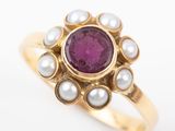 a close up of a gold ring with a pink stone and pearls