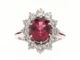 gros plan d'une bague avec une pierre rouge entourée de diamants blancs