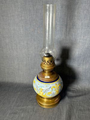 une lampe à huile à l'ancienne, avec un pied doré et un motif bleu et blanc