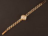 a gold watch on a black surface with a chain around it