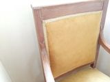 a wooden chair with a yellow seat next to a white wall
