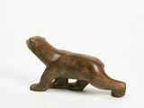 a small wooden bear figurine sitting on a white surface