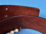 leather belt with pearl beads on a blue background