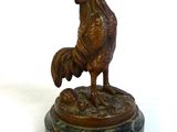 statue d'un coq posée sur un socle en marbre, sur fond blanc