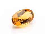 a close up of a yellow sapphire stone on a white surface